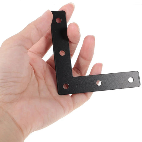 Hand holding a black L-shaped corner brace from the Flat Corner Braces 20 Pack - Beefy, Heavy Duty L Shape Right Angle Shelf Supports.