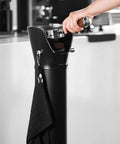 Heavy Duty Commercial Coffee Knock Box Featuring Hella Solid 6 Point 8 Liter ABS Grounds Disposal Bin, hand using knock box with towel.
