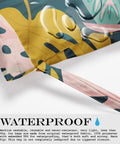 Close-up of waterproof wet bag with palm leaf tropical print and droplets, featuring strap detail, 26 by 32cm design.