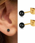 Dope Dainty Ball Stud Earrings Set For Women And Men, 3mm Tiny Black Hand Painted Enamel Color, Hypoallergenic Surgical Steel With 14K Gold Plated Option, Great For Second Piercings And Multiple Holes, Everyday Cute Jewelry. Black 3mm stud earring worn in ear and shown with gold-plated backing.