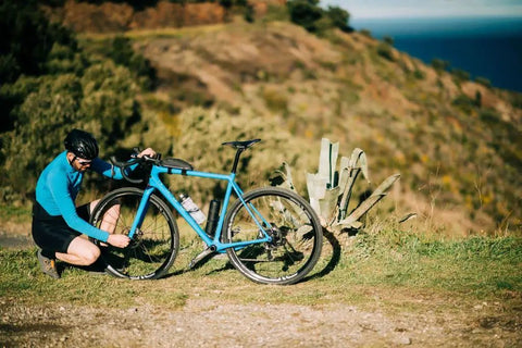 Cyclist adjusting bike beside mountain road, using 0.8L Waterproof Bike Tool Capsule For Bottle Cages Screw Cap Seal