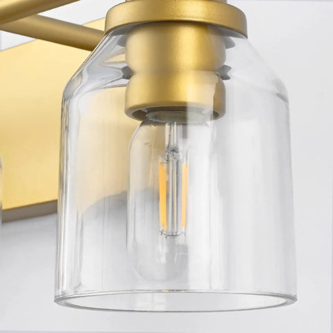 Close-up of Gold Three Light Bathroom Vanity Light Fixture Over Mirror Vintage Style Wall Light with clear glass shade and bulb.
