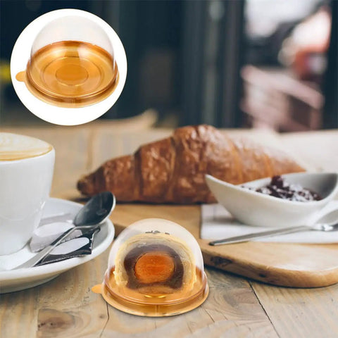 Clear Mini Cupcake Boxes With Dome Lids 100 Pack Plastic Treat Containers For Muffins Pastries And Cookies Bulk Packaging Easy To Carry For Birthday Party Supplies on a table with pastries and coffee cup.