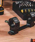 One Piece Bolt Action Scope Mount With Thirty Mil Medium Rings For Remington Seven Hundred Short Action on a workbench.