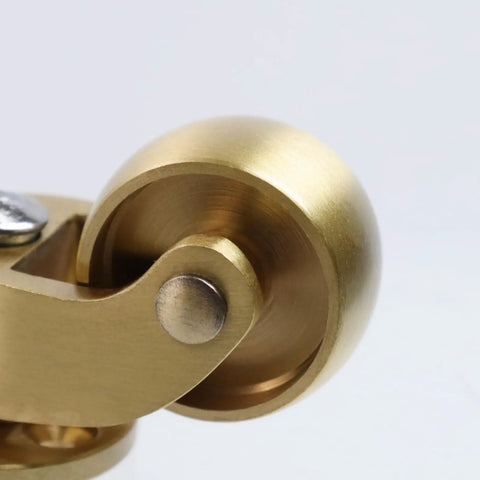 Close-up of Badass Solid Brass Swivel Casters for Floor Mats, showcasing polished brass wheel and smooth rotation.