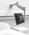 No Hassle Wall Mount Monitor Arm Straight Up Perfect For Your Gaming Office Setup Extra Long Gas Spring Mount in silver attached to wall with monitor tilted.