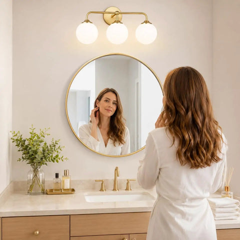 Dope Mid Century 3 Light Vanity Fixture With Smooth Brushed Gold Finish And Soft Milky White Glass Ball Shades in a bathroom setting.
