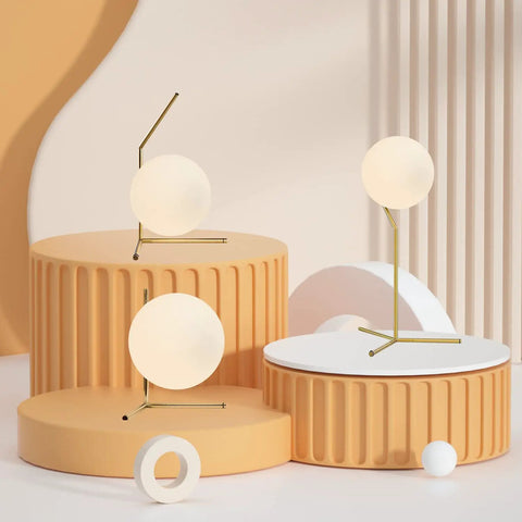 Mid Century Modern Brass Table Lamp With Gold Glass Globe on round platforms, featuring golden metal accents.