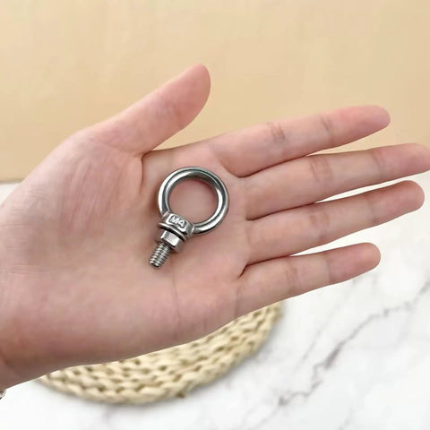 Six Pack 304 Stainless Steel M4 Eye Bolts With Matching Hex Nuts held in hand, showcasing sturdy design for rigging.