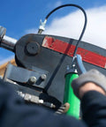 Lever Grip Grease Gun With Locking Coupler 20 Inch Heavy Duty Hose Inline Swivel, shown in use on industrial machinery