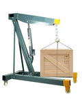 Heavy Duty Hydraulic Engine Hoist Folding Cherry Picker Shop Crane with wooden crate lifted, sturdy steel frame, adjustable to 2 tons.