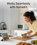Woman using HomeKit-enabled smart device in modern kitchen while cutting lemon, displaying seamless integration with technology.