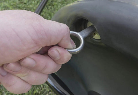 Close-up of hand removing drain plug from 18 By 24 Inch Poly Lawn Roller For Push Or Tow Black Built Tough Yard Roller With 250 Lb Water Capacity When Full