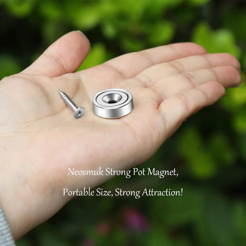 Hand holding Heavy Duty Neodymium Mounting Magnets With Screws, 40 Lbs Holding Power, Countersunk Holes, silver round magnet.