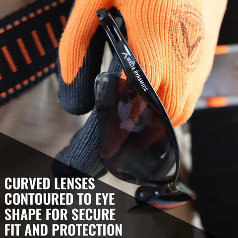 Anti Fog And Scratch Resistant Safety Glasses For Construction Pros And Everyday Workers On The Job With Tinted Lenses ANSI Z87 ISEA Certified Eye Protection For Men And Women Durable Lightweight Comfort Pack Of 12 held by person wearing gloves