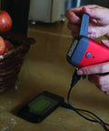 Person using Clipray Clip On Hand Crank Flashlight And Phone Charger For Emergency Prep No Batteries Needed One Minute Crank Delivers Ten Minutes Of Bright LED Light Cherry Red, charging phone.