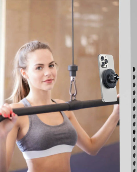 Gym Ready Magnetic Phone Holder With Alloy Base And Ball Joint Attaches To Metal Surfaces Dual Magnetic Mount For MagSafe iPhone 12 13 14 15 16 17 And Android With Metal Ring Secure Grip installed on gym equipment holding phone.