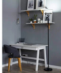 Lit 24W LED Daylight Floor Lamp Free Standing Uplight Torchiere next to a modern home office setup with shelves and gray chair