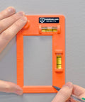 Hands using Pro-Grade Low Voltage Mounting Template 2-Pack For Fast Easy Horizontal Or Vertical Mounting With 4-Inch Ruler Bright Orange