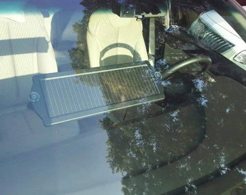Solar Car Battery Trickle Charger And Maintainer For 12V Vehicles installed on car dashboard behind windshield