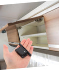 RV Compartment Latch Kit 4 Pack Durable Trailer Locks for Cabinet Doors held in hand with cabinet in background