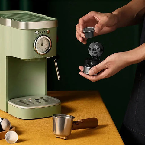 Hand holding a coffee capsule near a Heavy Duty No Hassle Electric Cappuccino Maker With Smooth Pour Milk Frother.