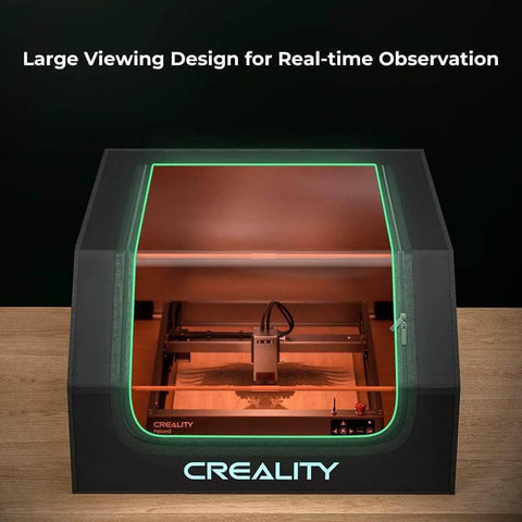Creality laser engraver enclosure front view; black cabinet with green-lit window and integrated fan