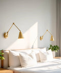 Ellis 18 Inch Two Pack Modern Gold Swing Arm Wall Sconces With Cone Shades Adjustable Heads above bed in bedroom, warm brass finish