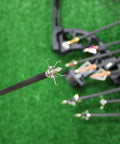 Close-up of a small game broadhead with spring-arm design on arrow, part of 12 pack for stump shooting and hunting on grass