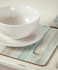 White bowl and plate on wooden pattern placemat with silverware