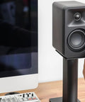 Person adjusting speaker on Rising Desktop Speaker Stands for Small to Medium Bookshelf Speakers and 2 to 4 Inch Studio Monitors, 8.3 Inch Tall, Black Pair, Rock Solid Steel Build and Anti Resonance Foam for Crisp, Clean Sound