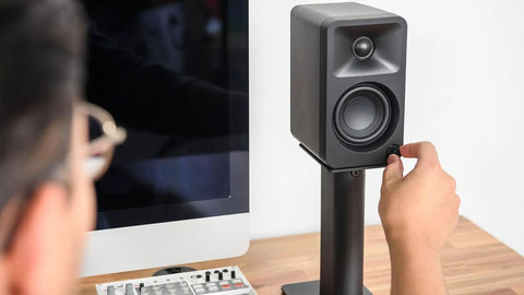 Person adjusting speaker on Rising Desktop Speaker Stands for Small to Medium Bookshelf Speakers and 2 to 4 Inch Studio Monitors, 8.3 Inch Tall, Black Pair, Rock Solid Steel Build and Anti Resonance Foam for Crisp, Clean Sound