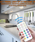 Hand holding remote for 13 Color LED Puck Lights With Remote Control Wireless Battery Powered Stick On Under Cabinet Lighting in kitchen