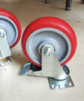 Heavy Duty Swivel Caster Wheels Four Pack Polyurethane Trolley Casters With Double Ball Bearings and Two Brake Plates, red wheels on steel brackets.