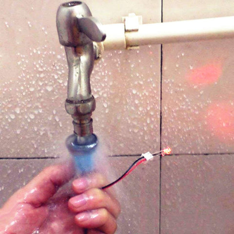 Person holding a small water turbine generator under running tap water, part of a Wind Hydroelectric Generator Model For STEM Classrooms.