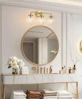Three Light Vanity Wall Sconce Over Mirror In Matte Gold Finish With Transparent Glass Ball Shade, Bathroom Setting