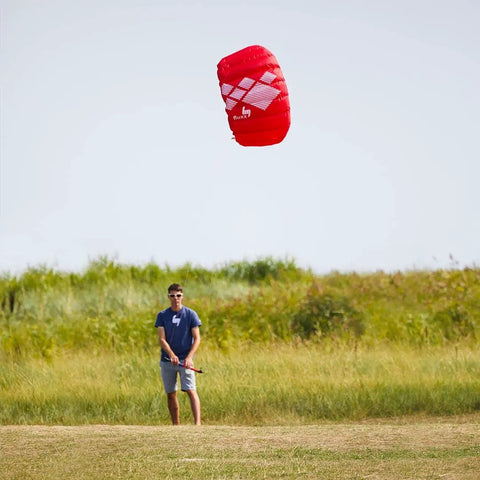 Person flying Fluxx 1.3 R2F Trainer Kite For Beginners with lines attached, showing easy launch and stable flight in open field
