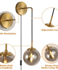 Set Of 2 Plug-In Wall Sconces With Brushed Brass Finish And Smoke Grey Glass Globes, detailing backplate, cord, and globes