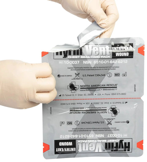 Front view of North American Rescue HyFin Vent Chest Seal Twin Pack being opened by gloved hands.