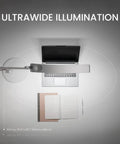 Ultrawide Desk Lamp With Eye Care Tech For Your Home Office Reading And Crafting Setup 13 Color Modes Dimmable Brightness Adjustable Arm Silver Finish 35 Inch Wide Desk Lighting Workspace Upgrade Lit showing top view illumination over laptop and book.