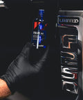 Carpro CQUARTZ UK 3.0 ceramic coating bottle, 50ml kit, held by gloved hand beside a car door handle