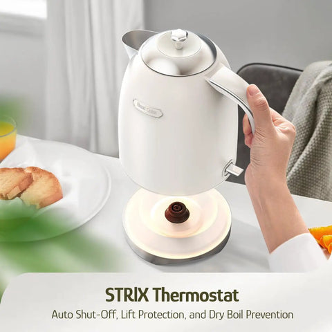 Person holding 1.7L Electric Kettle With Stainless Steel Interior, BPA-Free, 1200W Fast Boil, Cordless With Rotational Base, Automatic Shut Off, One-Touch LED, Pearl White on a tabletop with breakfast.