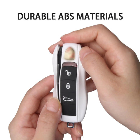 Hands holding Porsche Key Fob Cover Kit 3 Piece Painted Key Shell Set For Cayenne Panamera Macan 911 Boxster Cayman white, durable ABS material.
