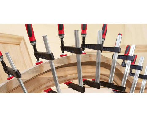 Cast Jaw Clamp For Woodworking And Carpentry F Style With Wood Handle in use on curved wood piece, heavy duty anti slip rail visible