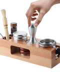 Level Up Your Home Bar Setup With This Premium Wooden Espresso Tamping Station Designed For 58mm Portafilters Featuring Killer Slots For Dosing Needles To Keep Your Smooth Shot Routine On Point. Image shows a wooden espresso tamping station with tools.