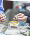 Galpada Solar Powered Jewelry Display Stand With Electric Rotating Turntable showcasing a gold bracelet with rings on a store counter.