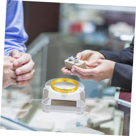 Galpada Solar Powered Jewelry Display Stand With Electric Rotating Turntable showcasing a gold bracelet with rings on a store counter.