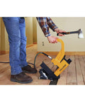 Person using a Flooring Nailer Rolling Base With Tool Free Thickness Adjustment on wood floor, showing non-marring wheels