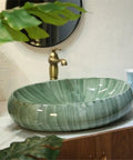 USZWBY Green Ceramic Oval Vessel Sink for Bathroom Balcony Outdoor Counter Top Vanity placed on a countertop with a faucet.