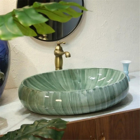 USZWBY Green Ceramic Oval Vessel Sink for Bathroom Balcony Outdoor Counter Top Vanity placed on a countertop with a faucet.